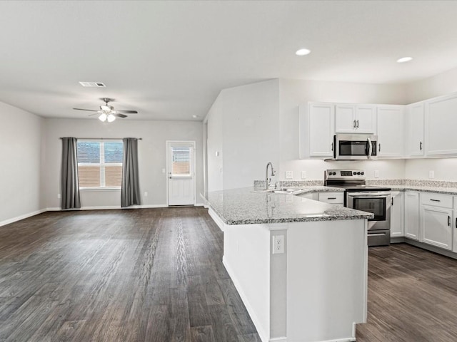 kitchen featuring light stone countertops, white cabinetry, sink, stainless steel appliances, and kitchen peninsula