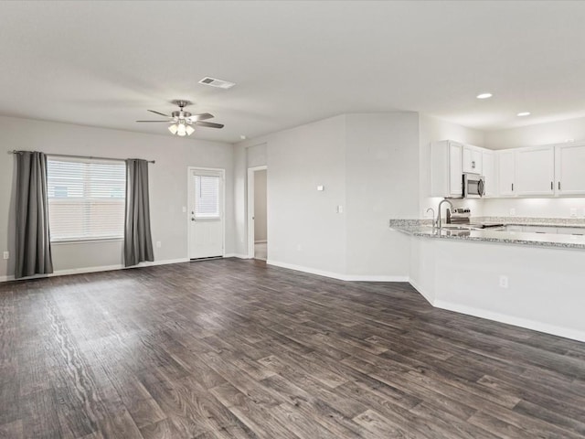 unfurnished living room with ceiling fan and dark wood-type flooring