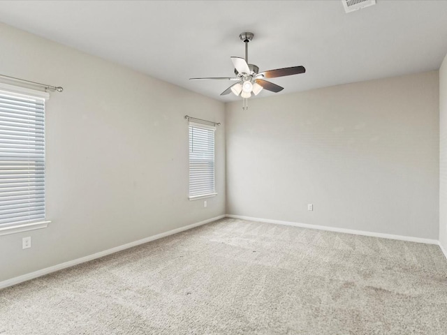 carpeted spare room featuring plenty of natural light and ceiling fan