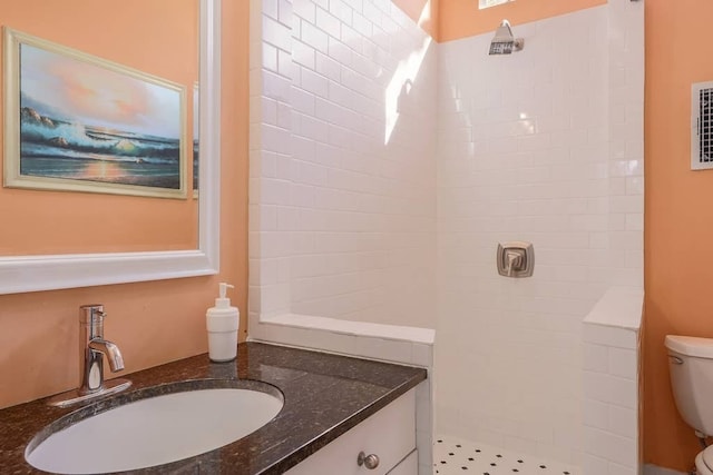 bathroom featuring toilet, vanity, and a tile shower