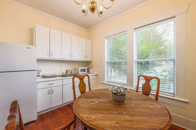 dining room featuring dark wood-type flooring, sink, crown molding, and an inviting chandelier