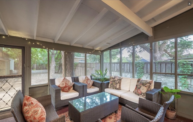 sunroom featuring lofted ceiling with beams and a wealth of natural light