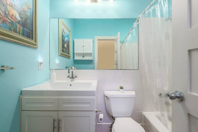 full bathroom with toilet, vanity, and shower / bathtub combination with curtain