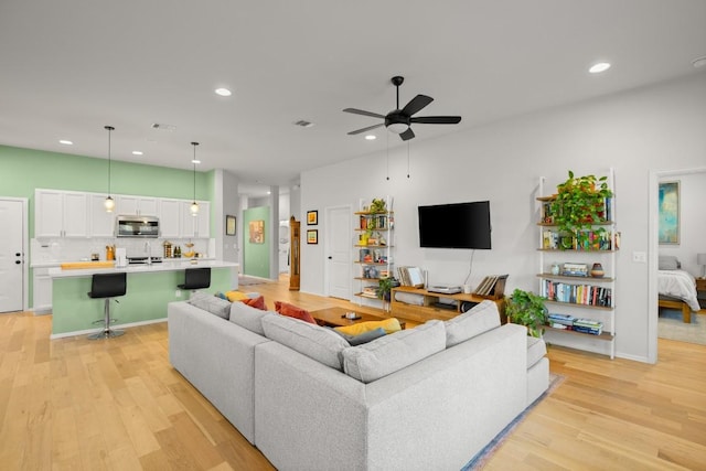 living room featuring ceiling fan and light hardwood / wood-style flooring