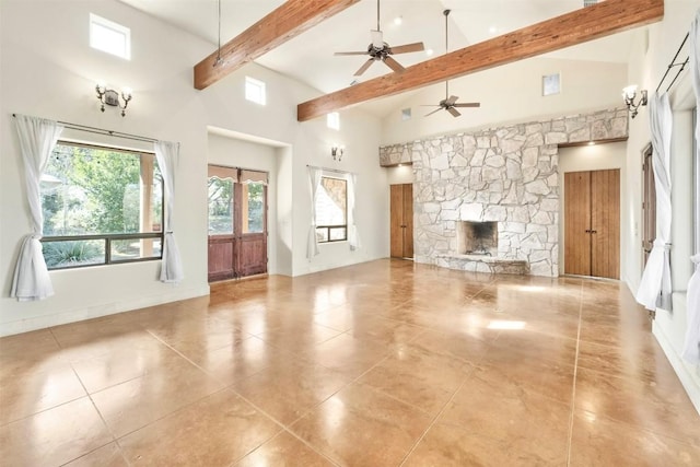 unfurnished living room with a fireplace, beam ceiling, ceiling fan, and a high ceiling