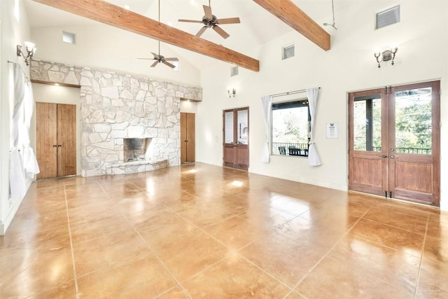 unfurnished living room with french doors, ceiling fan, a towering ceiling, a fireplace, and beamed ceiling