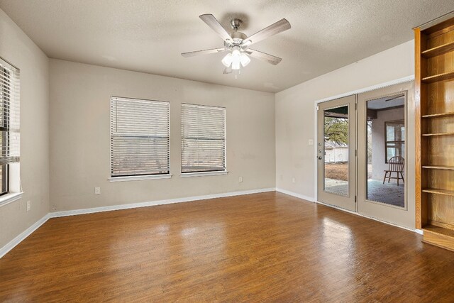 spare room with a textured ceiling, ceiling fan, and dark wood-type flooring