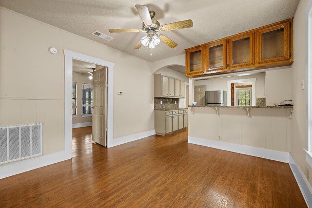 unfurnished living room with hardwood / wood-style floors, ceiling fan, and a textured ceiling