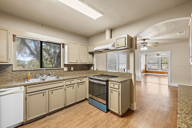 kitchen with stainless steel range with electric cooktop, cream cabinets, white dishwasher, sink, and a textured ceiling