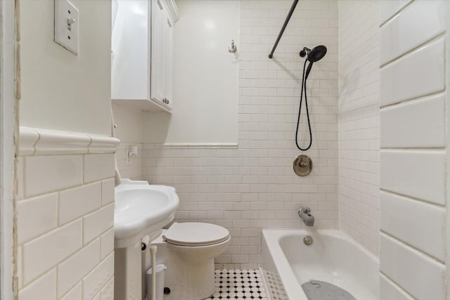 bathroom featuring tile patterned flooring, tiled shower / bath combo, tile walls, and toilet