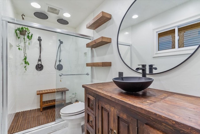 bathroom with vanity, toilet, and a shower with door