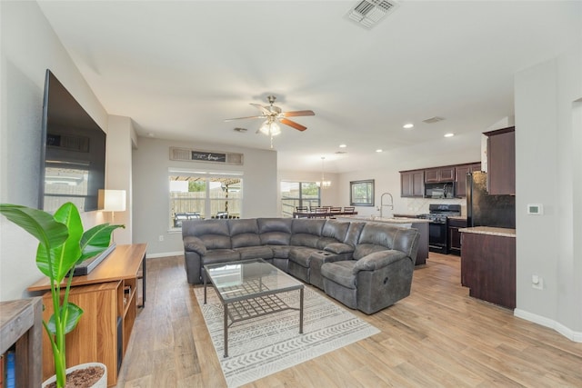 living room featuring ceiling fan, light hardwood / wood-style flooring, and sink