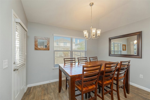 dining space with dark wood-type flooring and a chandelier