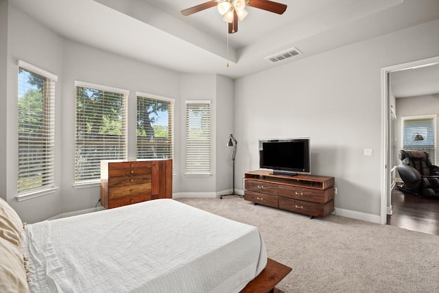 bedroom featuring light colored carpet, a raised ceiling, and ceiling fan