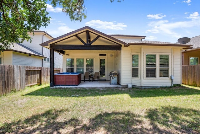 back of house featuring a lawn, a patio area, and a hot tub