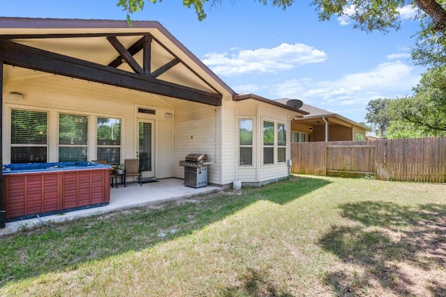 rear view of property featuring a yard, a hot tub, and a patio area