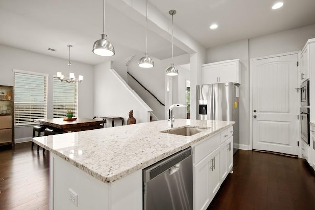 kitchen with light stone countertops, sink, stainless steel appliances, a center island with sink, and white cabinets