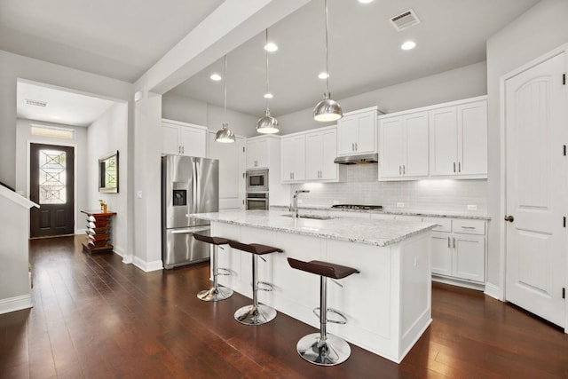 kitchen with stainless steel appliances, a kitchen island with sink, sink, pendant lighting, and white cabinets