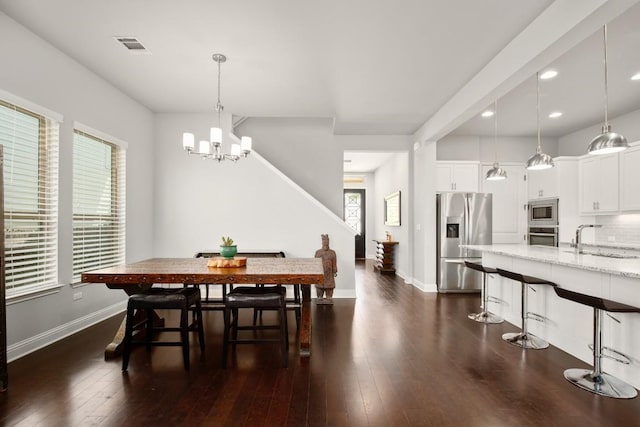 dining space with dark hardwood / wood-style flooring, a wealth of natural light, sink, and an inviting chandelier