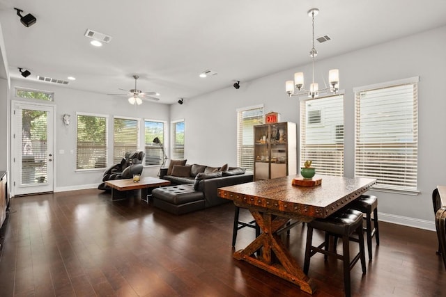 dining room with ceiling fan with notable chandelier and dark hardwood / wood-style floors