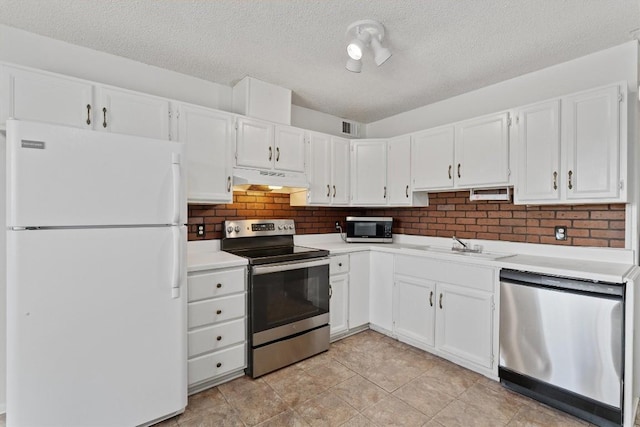 kitchen with appliances with stainless steel finishes, a textured ceiling, white cabinetry, and sink