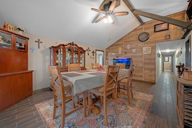 dining space with dark hardwood / wood-style flooring, lofted ceiling with beams, ceiling fan, and wooden walls