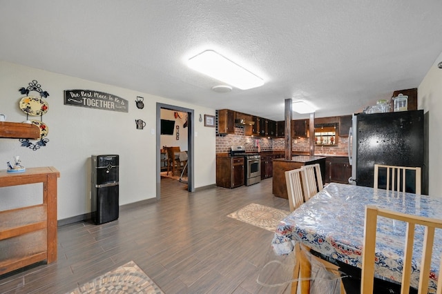 kitchen featuring backsplash, black fridge, dark brown cabinets, and stainless steel range with gas stovetop