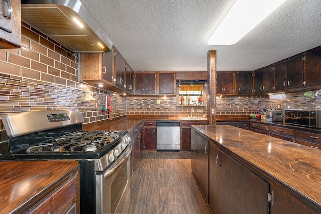 kitchen with stainless steel appliances, wall chimney range hood, a textured ceiling, decorative backsplash, and dark brown cabinets