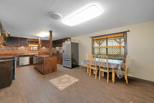 kitchen featuring decorative backsplash, appliances with stainless steel finishes, light wood-type flooring, dark brown cabinetry, and a kitchen island