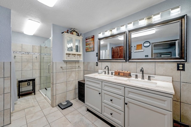 bathroom featuring tile patterned floors, an enclosed shower, vanity, a textured ceiling, and tile walls