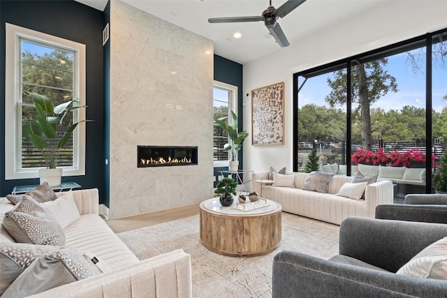 living room with a fireplace, light hardwood / wood-style flooring, and ceiling fan