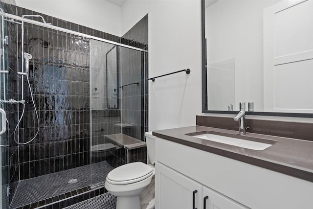 bathroom featuring tile patterned flooring, vanity, a shower with shower door, and toilet