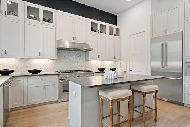 kitchen featuring white cabinetry, a center island, light hardwood / wood-style flooring, a kitchen bar, and high end appliances