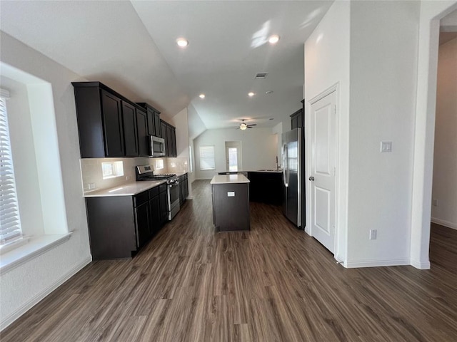 kitchen with stainless steel appliances, ceiling fan, dark hardwood / wood-style floors, a kitchen island, and lofted ceiling