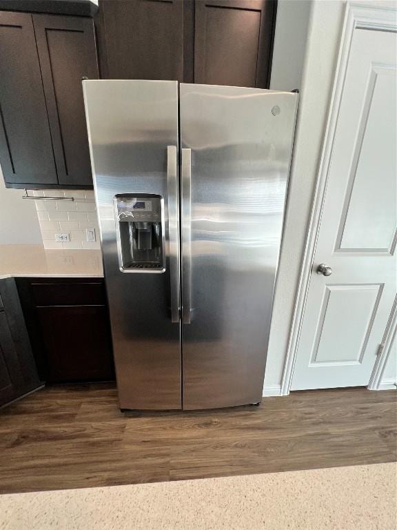 kitchen with backsplash, stainless steel fridge, dark brown cabinets, and wood-type flooring