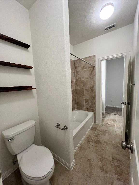 bathroom featuring tiled shower / bath combo and toilet