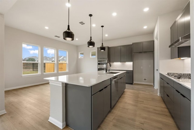 kitchen with a spacious island, hanging light fixtures, tasteful backsplash, light hardwood / wood-style floors, and stainless steel appliances