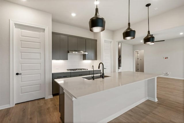 kitchen featuring pendant lighting, sink, a kitchen island with sink, and hardwood / wood-style flooring