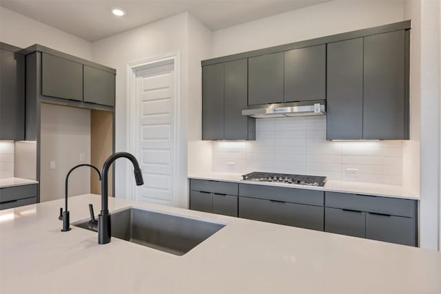 kitchen featuring stainless steel gas stovetop, gray cabinets, sink, and tasteful backsplash