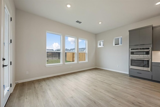 kitchen featuring light hardwood / wood-style floors, gray cabinets, and stainless steel double oven