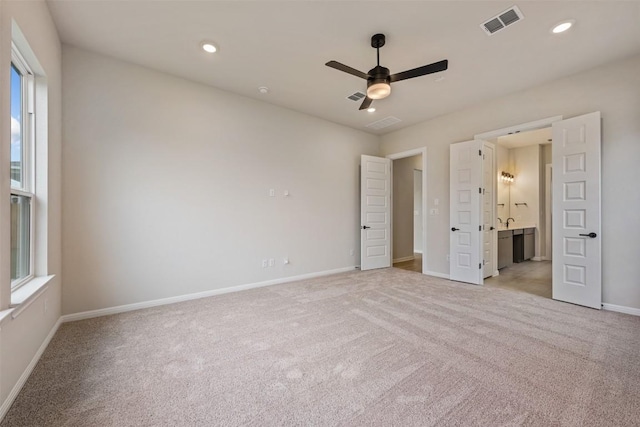 unfurnished bedroom with connected bathroom, ceiling fan, and light colored carpet