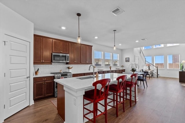 kitchen featuring a kitchen breakfast bar, stainless steel appliances, a kitchen island with sink, sink, and pendant lighting