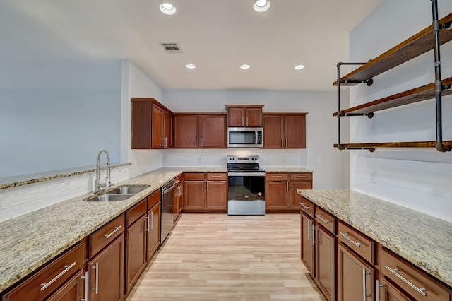 kitchen featuring backsplash, sink, light hardwood / wood-style flooring, light stone counters, and stainless steel appliances