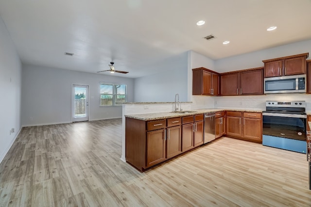 kitchen featuring kitchen peninsula, stainless steel appliances, ceiling fan, sink, and light hardwood / wood-style flooring