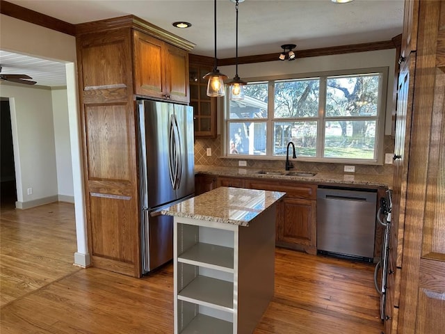 kitchen featuring decorative backsplash, light stone counters, stainless steel appliances, sink, and a kitchen island