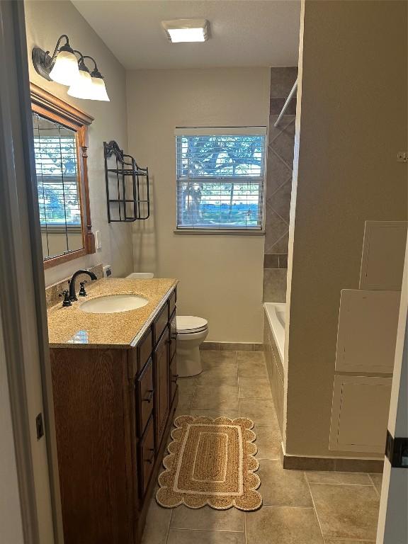 full bathroom featuring tile patterned flooring, vanity, toilet, and tiled shower / bath