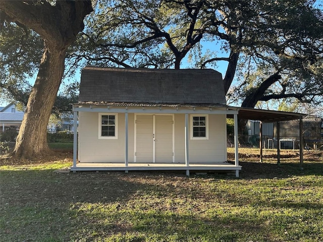 view of outdoor structure with a carport and a lawn