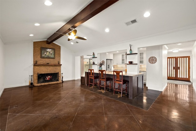 bar with lofted ceiling with beams, crown molding, a brick fireplace, ceiling fan, and stainless steel fridge with ice dispenser