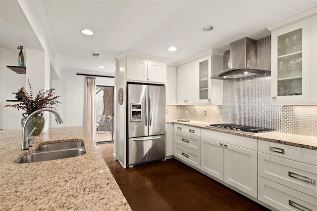 kitchen with light stone countertops, appliances with stainless steel finishes, wall chimney exhaust hood, and sink