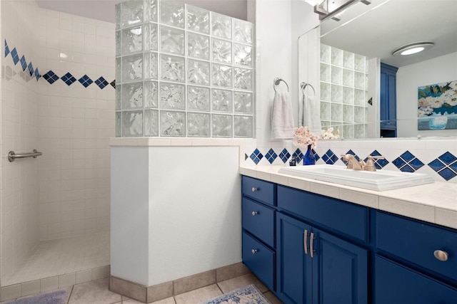 bathroom featuring backsplash, tile patterned floors, vanity, and tiled shower